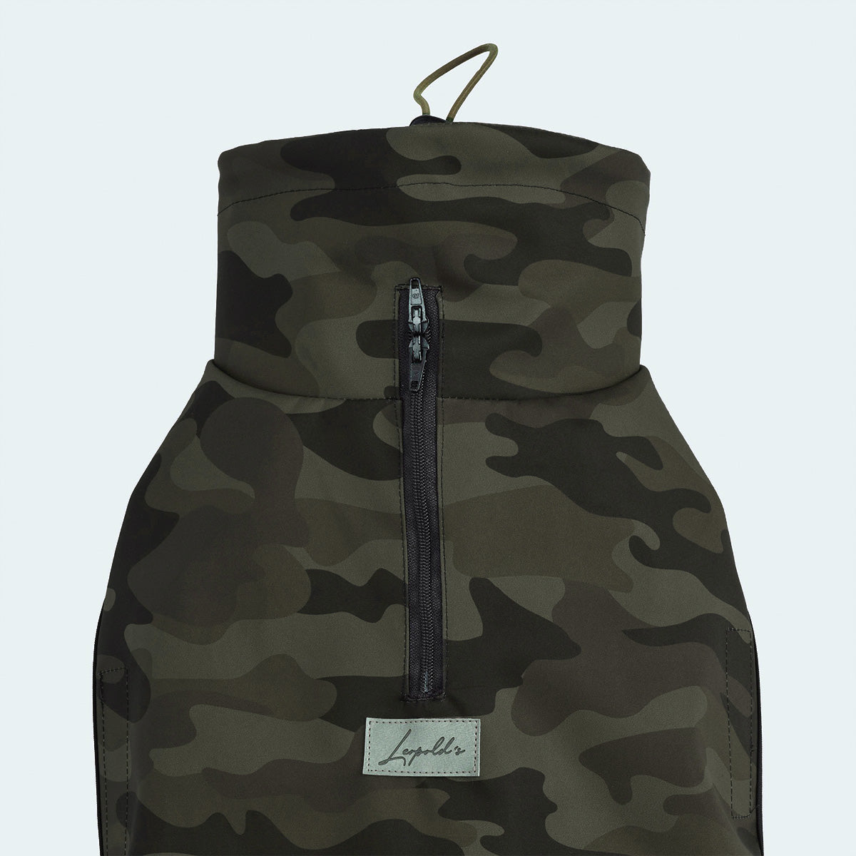 Leopold's Finest | Funktionaler Windbreaker für Dackel und kleine Hunde aus wind- und wasserabweisendem Material mit dunkelgrünem Camouflage-Muster. Detailansicht vom Reißverschluss und Logo.